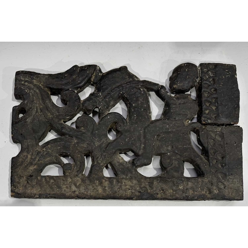 287 - A carved wood panel depicting a figure on horseback amongst a scrolling floriate background, tarred ... 