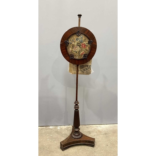 543 - A regency rosewood pole screen, tri-form base on winged feet, rising to a reeded baluster to a taper... 