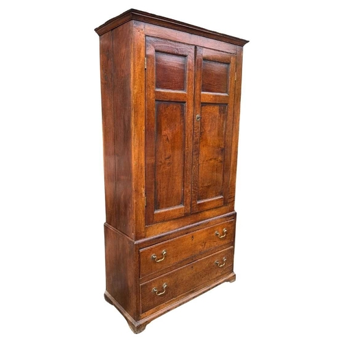 558 - An 18th century oak livery cupboard or linen press arranged as two panelled doors above two drawers ... 