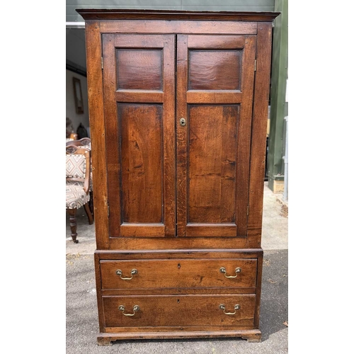 558 - An 18th century oak livery cupboard or linen press arranged as two panelled doors above two drawers ... 