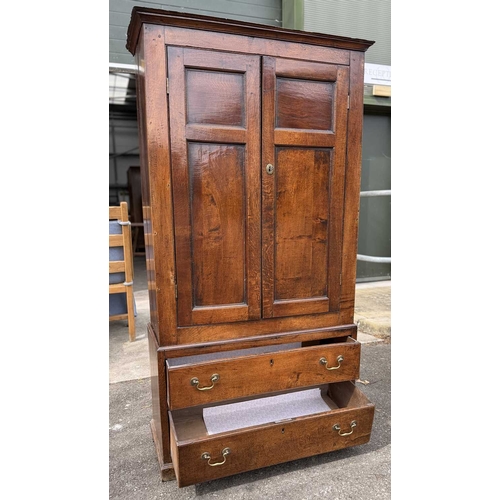 558 - An 18th century oak livery cupboard or linen press arranged as two panelled doors above two drawers ... 