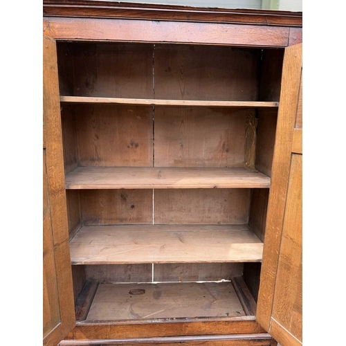 558 - An 18th century oak livery cupboard or linen press arranged as two panelled doors above two drawers ... 