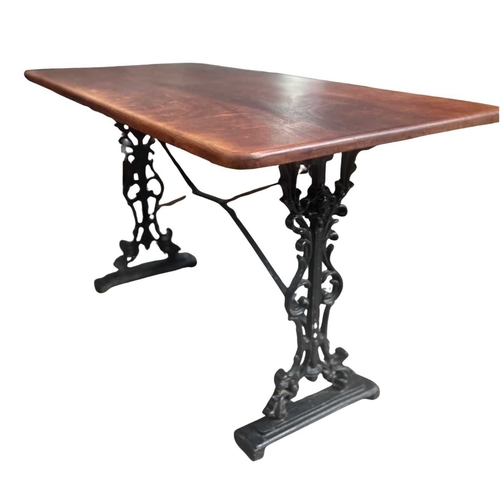 587 - A mahogany and cast iron table, the three plank top with rounded corners, supported on a base of two... 