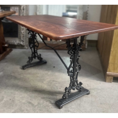 587 - A mahogany and cast iron table, the three plank top with rounded corners, supported on a base of two... 