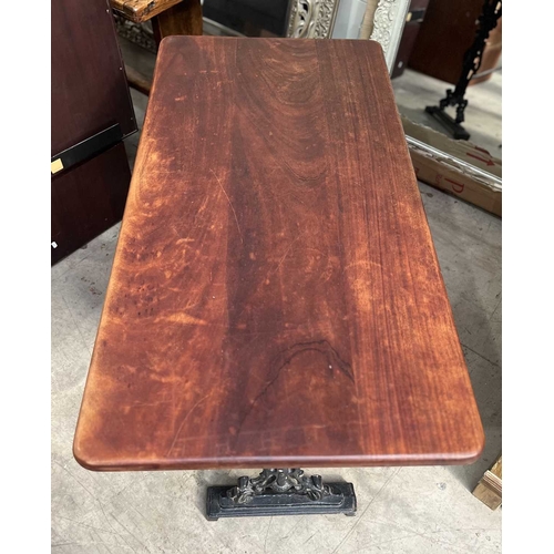 587 - A mahogany and cast iron table, the three plank top with rounded corners, supported on a base of two... 