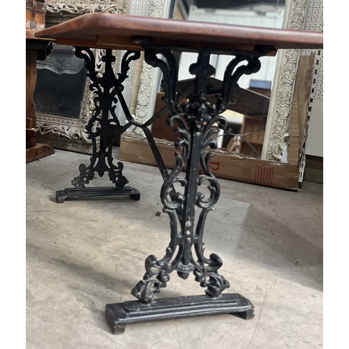 587 - A mahogany and cast iron table, the three plank top with rounded corners, supported on a base of two... 