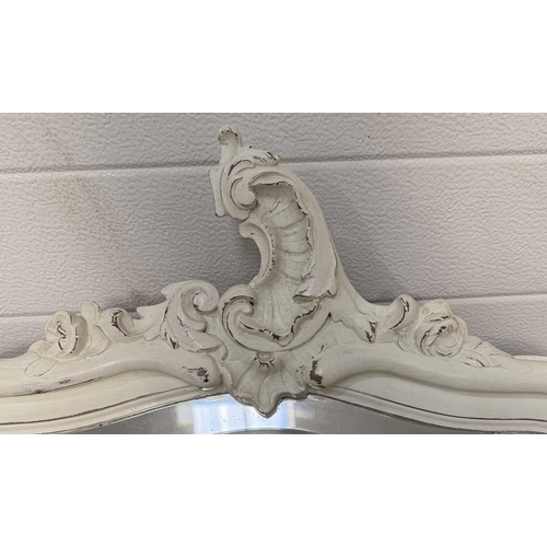 600 - A painted wooden wall mirror, bombe form with asymmetric rococo carving to the top, bevelled glass p... 