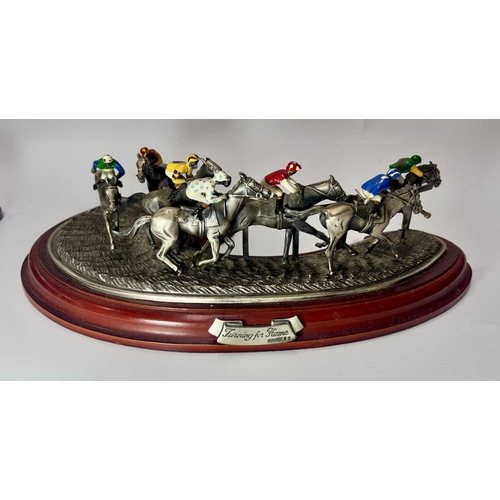 84 - A small group of hand painted, cast metal figurines of jockeys racing horses, mounted to wooden plin... 