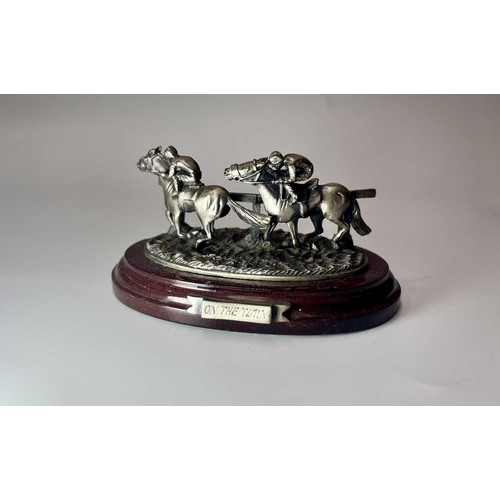 84 - A small group of hand painted, cast metal figurines of jockeys racing horses, mounted to wooden plin... 
