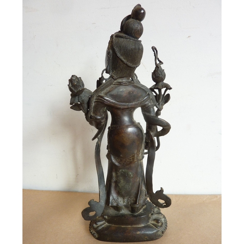 119 - A patinated bronze model of a female deity in the Sino-Tibetan style; the figure standing upon a lot... 