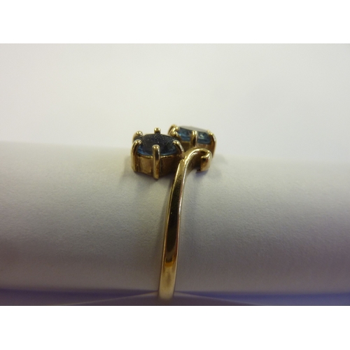 185 - A 9-carat gold, blue stone, crossover ring