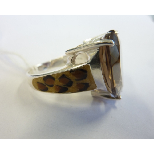 208 - A heavy silver ring unusually modelled with ''leopard skin'' style shoulders and centrally mounted w... 