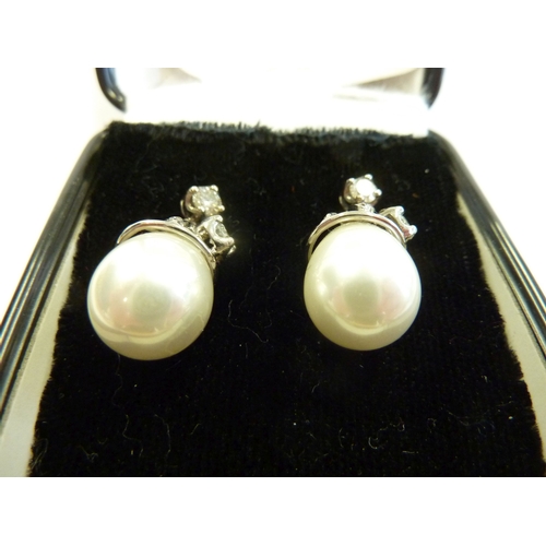 214 - A pair of white gold and diamond earrings; the diamond studs supporting diamonds and pearls