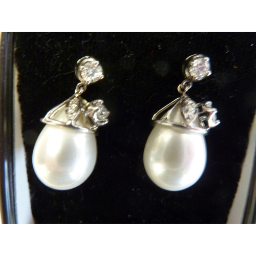 214 - A pair of white gold and diamond earrings; the diamond studs supporting diamonds and pearls