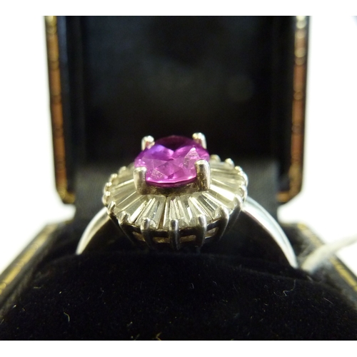 233 - A boxed ring centrally set with an oval pink stone surrounded by baguette-style stones