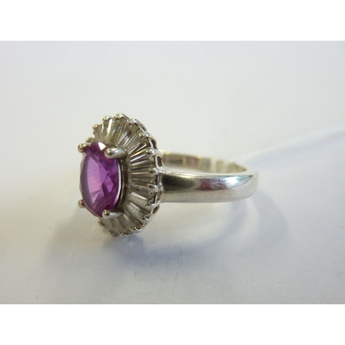 233 - A boxed ring centrally set with an oval pink stone surrounded by baguette-style stones