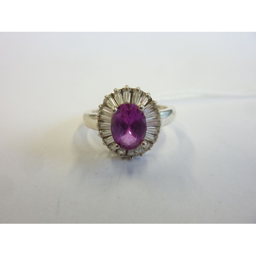 233 - A boxed ring centrally set with an oval pink stone surrounded by baguette-style stones