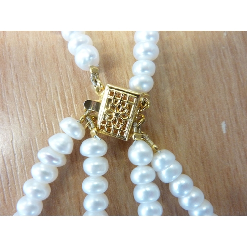 236 - A triple string of river pearls with pierced gilt-metal clasp