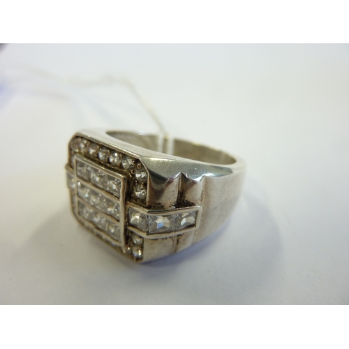 241 - A heavy silver ring set with a profusion of white stones in a belt buckle design