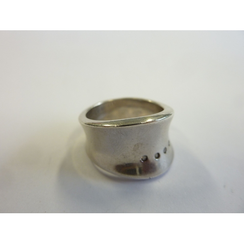 243 - A heavy hallmarked waisted and concave shaped white metal ring set with four small horizontal white ... 