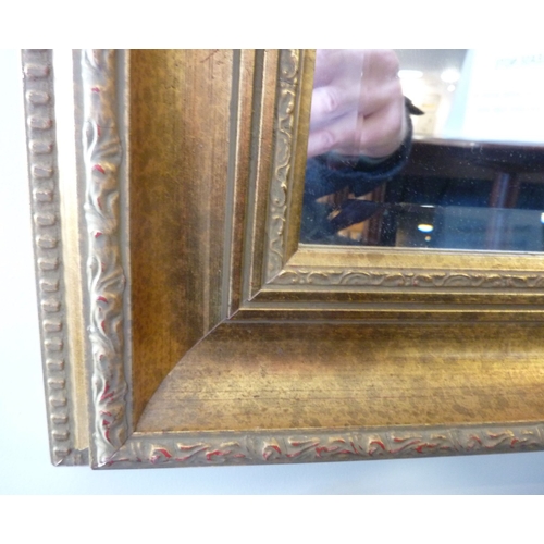 432 - A decorative wall hanging lounge/hallway mirror, moulded gilt frame surrounding a hand-bevelled plat... 