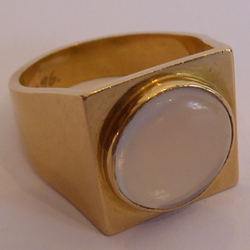 125 - A gentleman's heavy yellow-metal ring (marked 750); centrally set with a circular moonstone and the ... 