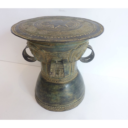 70 - An interesting patinated circular bronze stand; decorated with masks in relief and with four circula... 