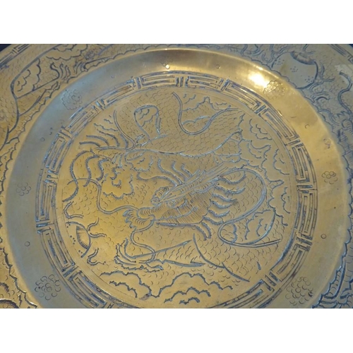 113 - An early/mid 20th century circular Chinese brass dish; centrally engraved with a dragon and with a b... 