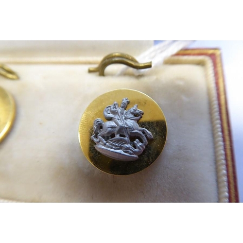 240 - A cased set of three gold buttons with fasteners; base metal motifs of George slaying the dragon, ma... 