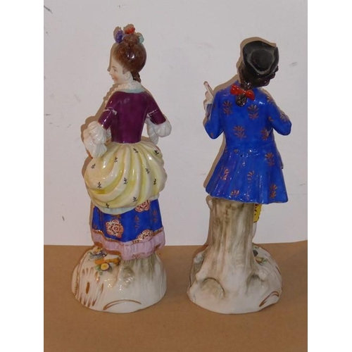 25 - A pair of late 19th century hand-decorated continental porcelain figures; the lady with hair tied up... 