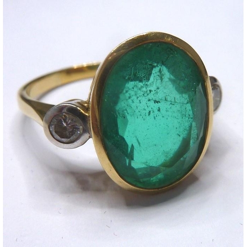 253 - An 18-carat ladies ring set with a large emerald (15mm x 12mm, approx. 6 carat) flanked by two diamo... 