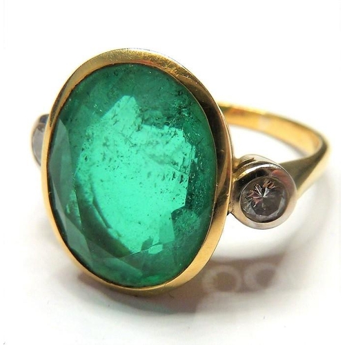 253 - An 18-carat ladies ring set with a large emerald (15mm x 12mm, approx. 6 carat) flanked by two diamo... 