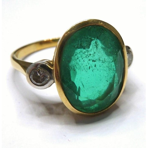 253 - An 18-carat ladies ring set with a large emerald (15mm x 12mm, approx. 6 carat) flanked by two diamo... 