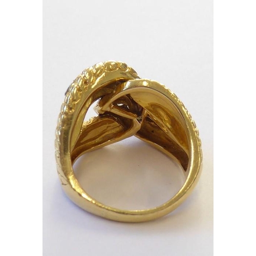 313 - An early 1970s 18 carat yellow gold and diamond-set dress ring, the textured double knot design set ... 