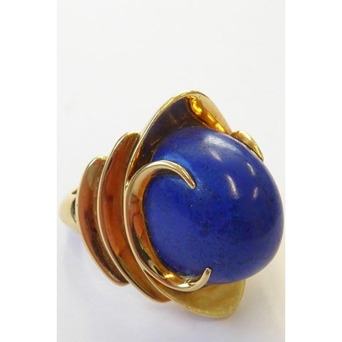 322 - A stylish 1960s lapis lazuli dress ring, the oval lapis cabochon set above a concave navette plaque ... 