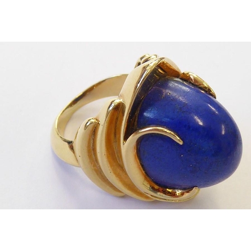 322 - A stylish 1960s lapis lazuli dress ring, the oval lapis cabochon set above a concave navette plaque ... 