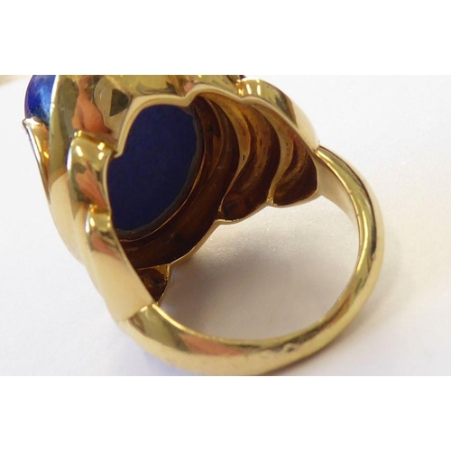 322 - A stylish 1960s lapis lazuli dress ring, the oval lapis cabochon set above a concave navette plaque ... 