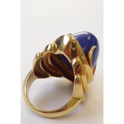 322 - A stylish 1960s lapis lazuli dress ring, the oval lapis cabochon set above a concave navette plaque ... 