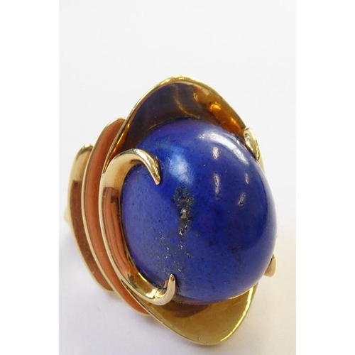 322 - A stylish 1960s lapis lazuli dress ring, the oval lapis cabochon set above a concave navette plaque ... 