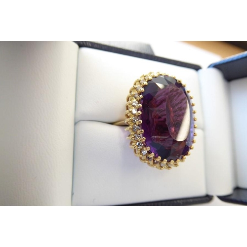 344 - An amethyst and diamond-set dress ring, the oval mixed-cut amethyst claw-set above the brilliant-cut... 