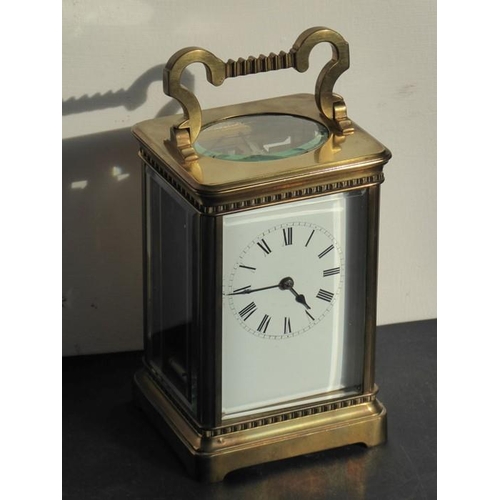 401 - An early 20th century brass carriage clock timepiece; the swing handle above an enamel dial with Rom... 