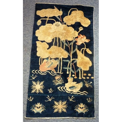 482 - A blue Tibetan Baotou Suiyuan rug decorated with two Mandarin ducks on a lotus pond, circa 1920 (123... 