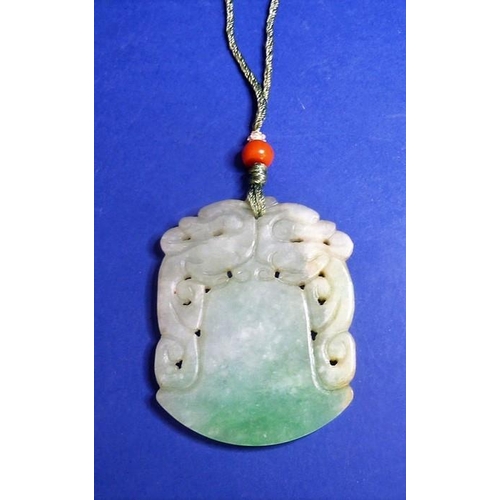 489 - A jadeite axe-form double dragon pendant on silk cord with a red-coral bead bound with seed pearls (... 