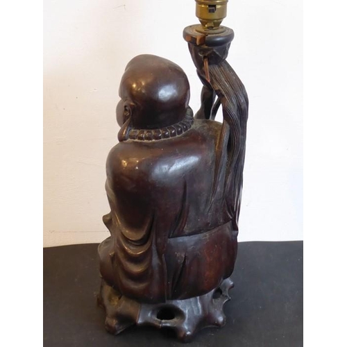 505 - An early 20th century Chinese hardwood carving of a Lohan seated and in his left hand a long bead ea... 