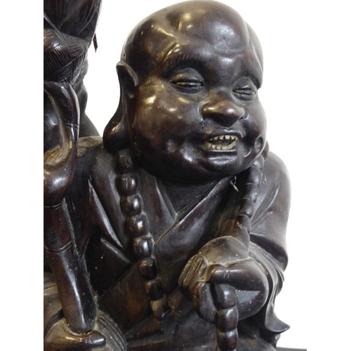 505 - An early 20th century Chinese hardwood carving of a Lohan seated and in his left hand a long bead ea... 