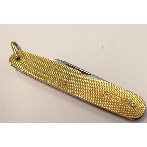 525 - A double penknife with 9-carat yellow-gold sides having engine-turned decoration; with hinged suspen... 