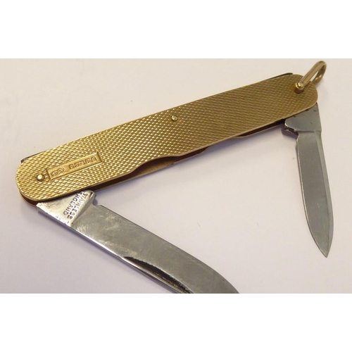 525 - A double penknife with 9-carat yellow-gold sides having engine-turned decoration; with hinged suspen... 