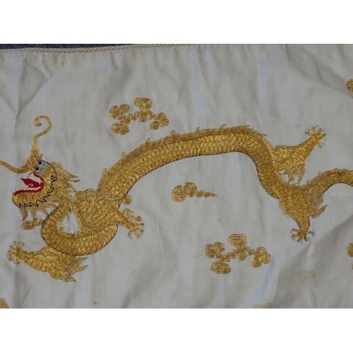 531 - A Chinese silk work wall hanging decorated with gold stitching with two dragons contesting a central... 