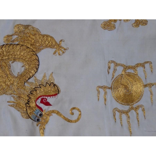 531 - A Chinese silk work wall hanging decorated with gold stitching with two dragons contesting a central... 