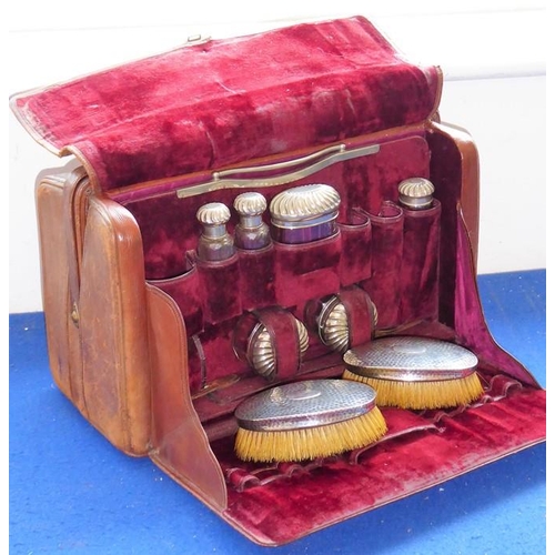 558 - An early 20th brown-leather vanity case; two compartments, one compartment opening to reveal various... 